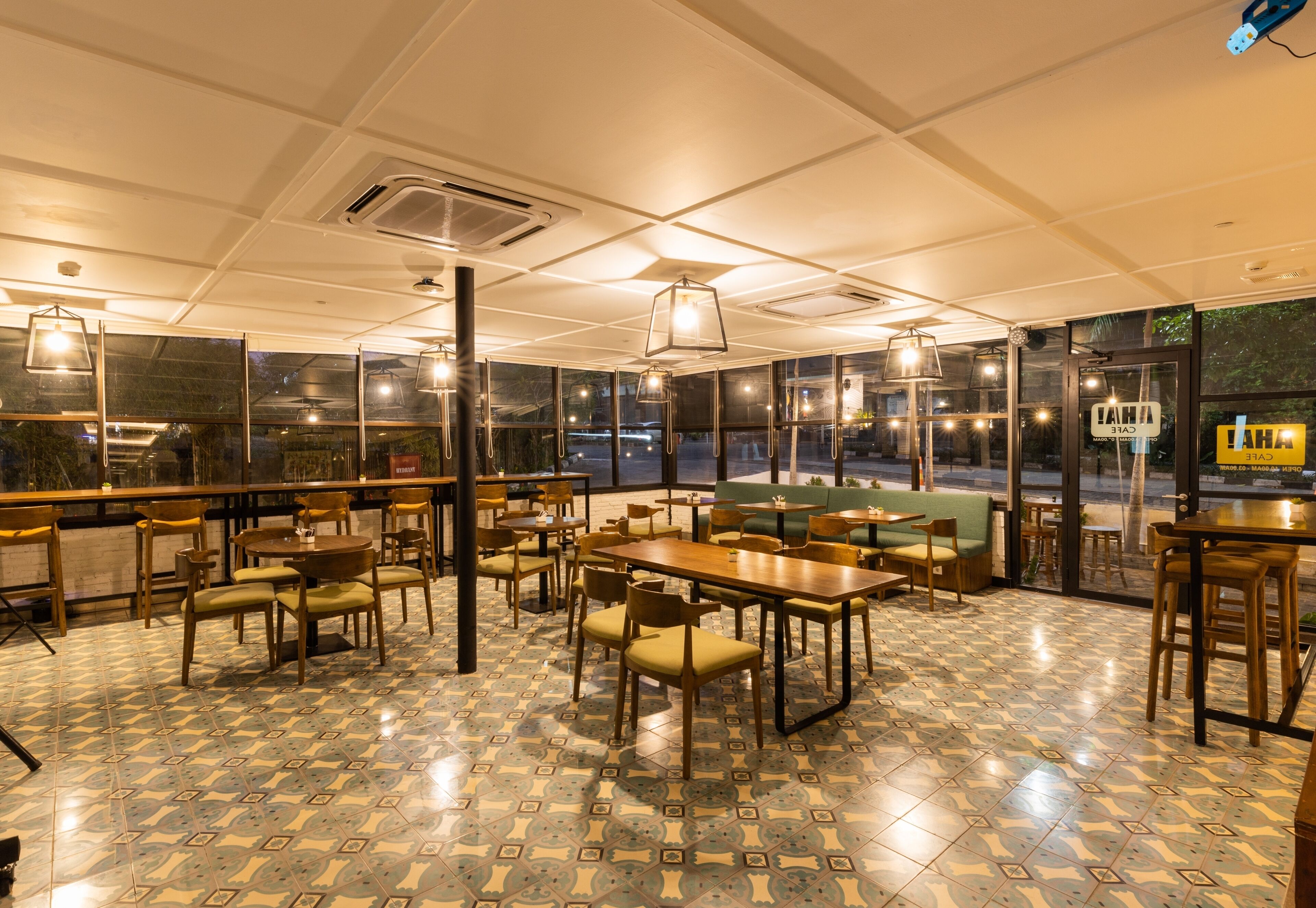 Un ristorante con pavimento piastrellato, tavoli e sedie in legno, e lampadari a sospensione.