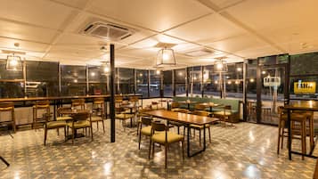 Un ristorante con pavimento piastrellato, tavoli e sedie in legno, e lampadari a sospensione.