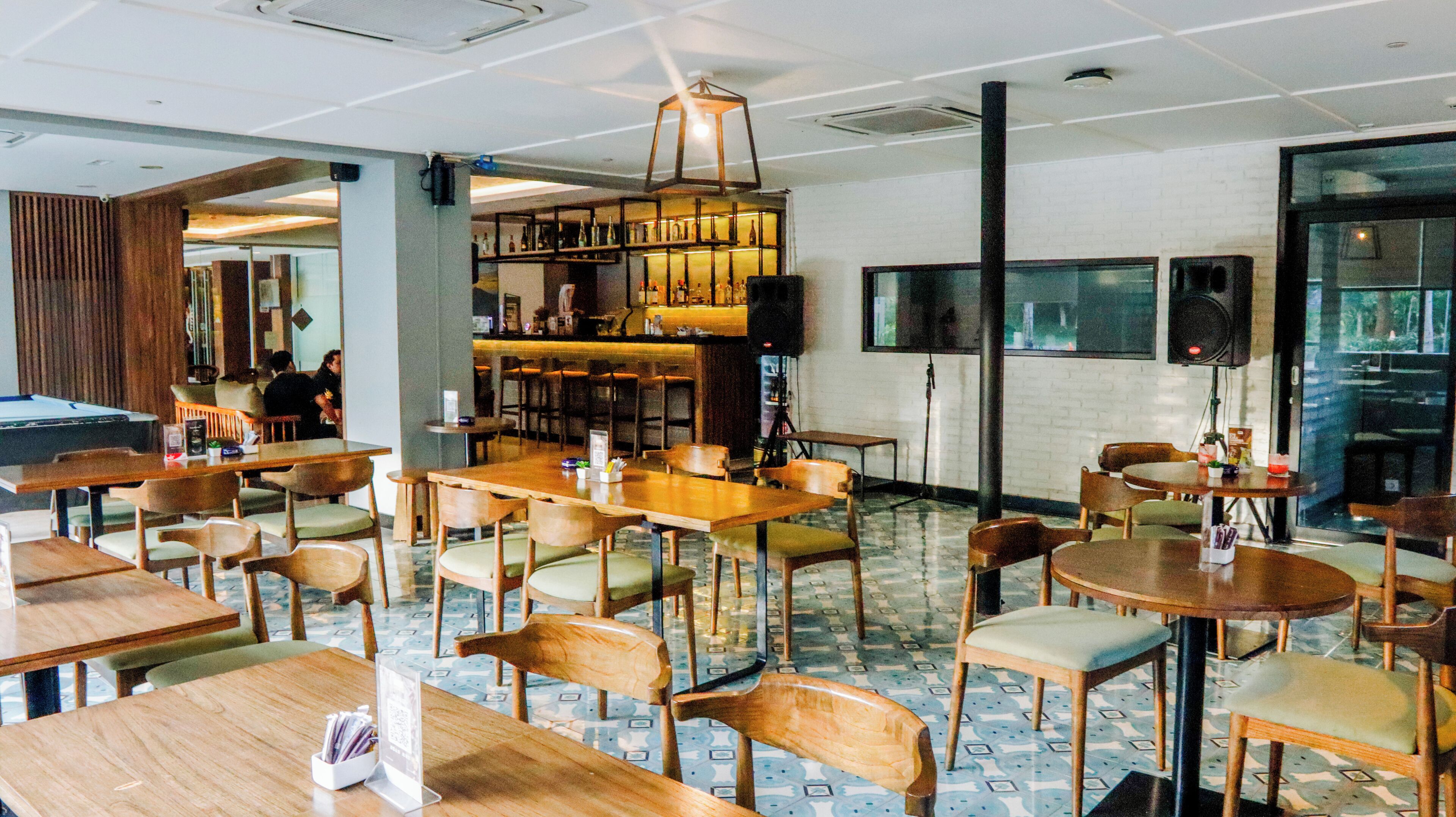 A restaurant with wooden tables and chairs, a bar area, and a pool table.