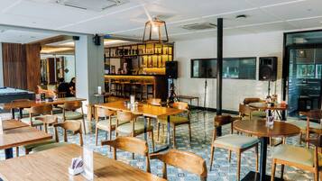 Een restaurant met houten tafels en stoelen, een bar en een pooltafel.