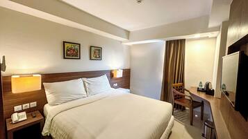 Habitación de hotel con una cama grande, mesitas de noche con lámparas, un escritorio con silla y una televisión.