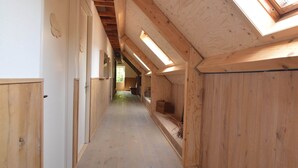 Ein schmaler Korridor mit Holzwänden und einer geneigten Decke mit Oberlichtern.