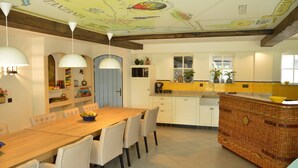 Eine geräumige Küche mit einem Holzespeisetisch, weißen Stühlen und einer Decke mit Kartenmuster.