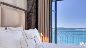 A hotel room with a large bed, a view of the sea, and a balcony with a railing. - Grand Hotel Kalamata (Kalamata)