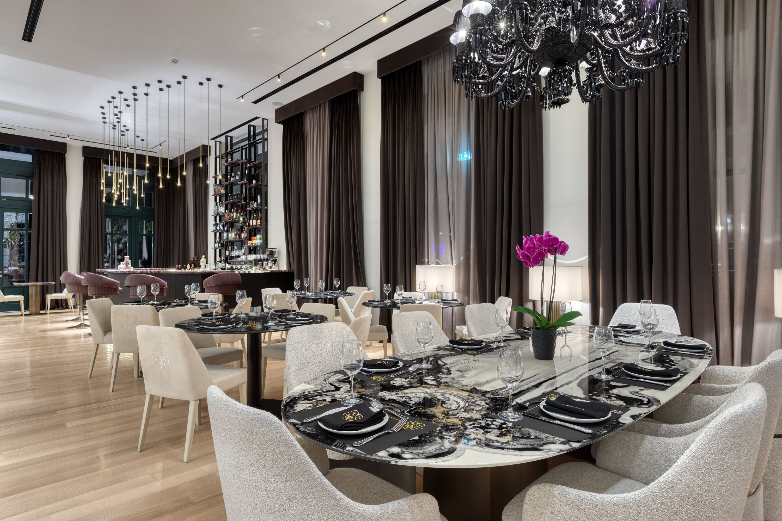 A modern dining area with a large round table set for a meal, surrounded by high-backed chairs.