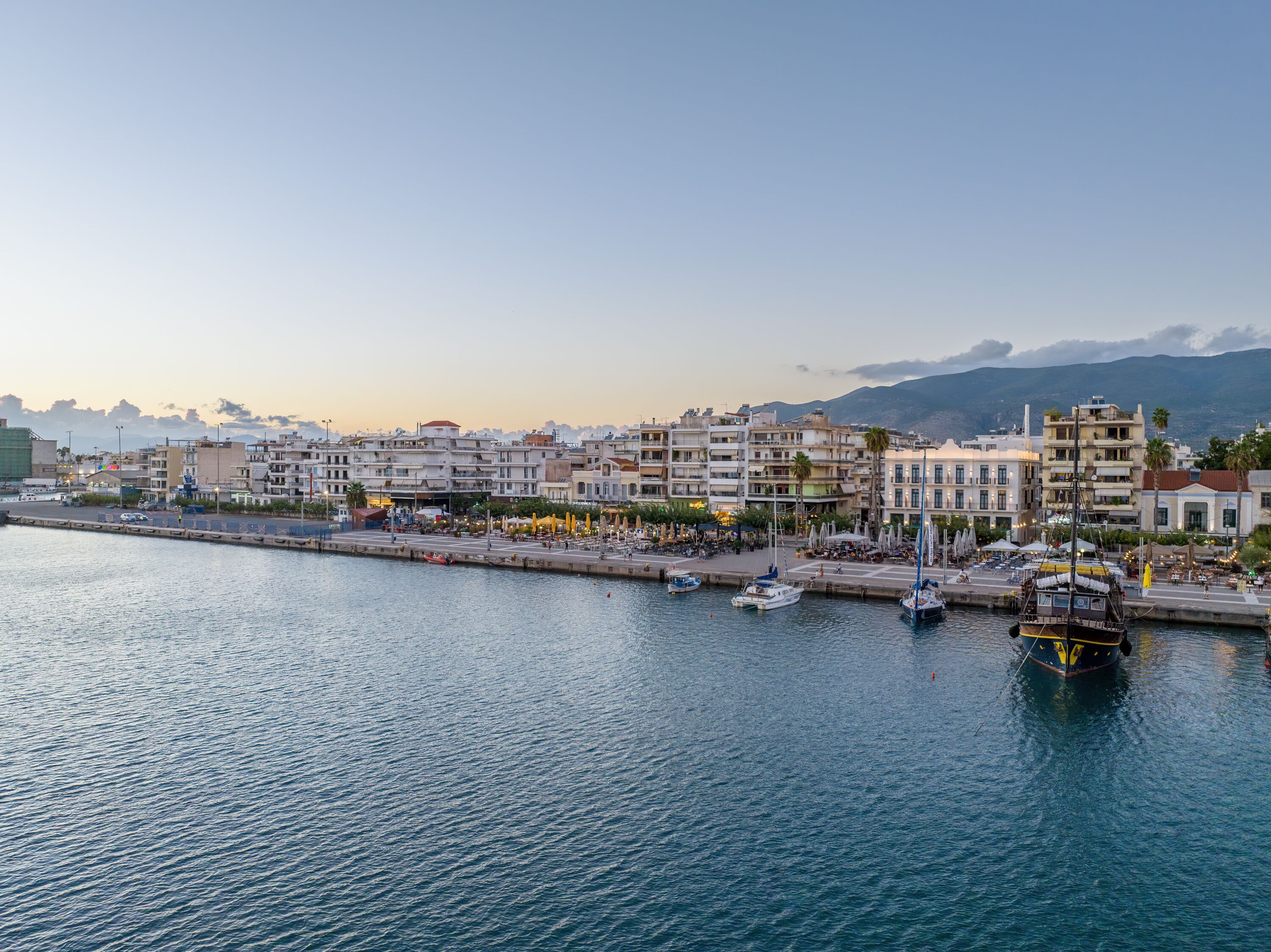 A coastal cityscape with a marina, waterfront buildings, and a clear sky.