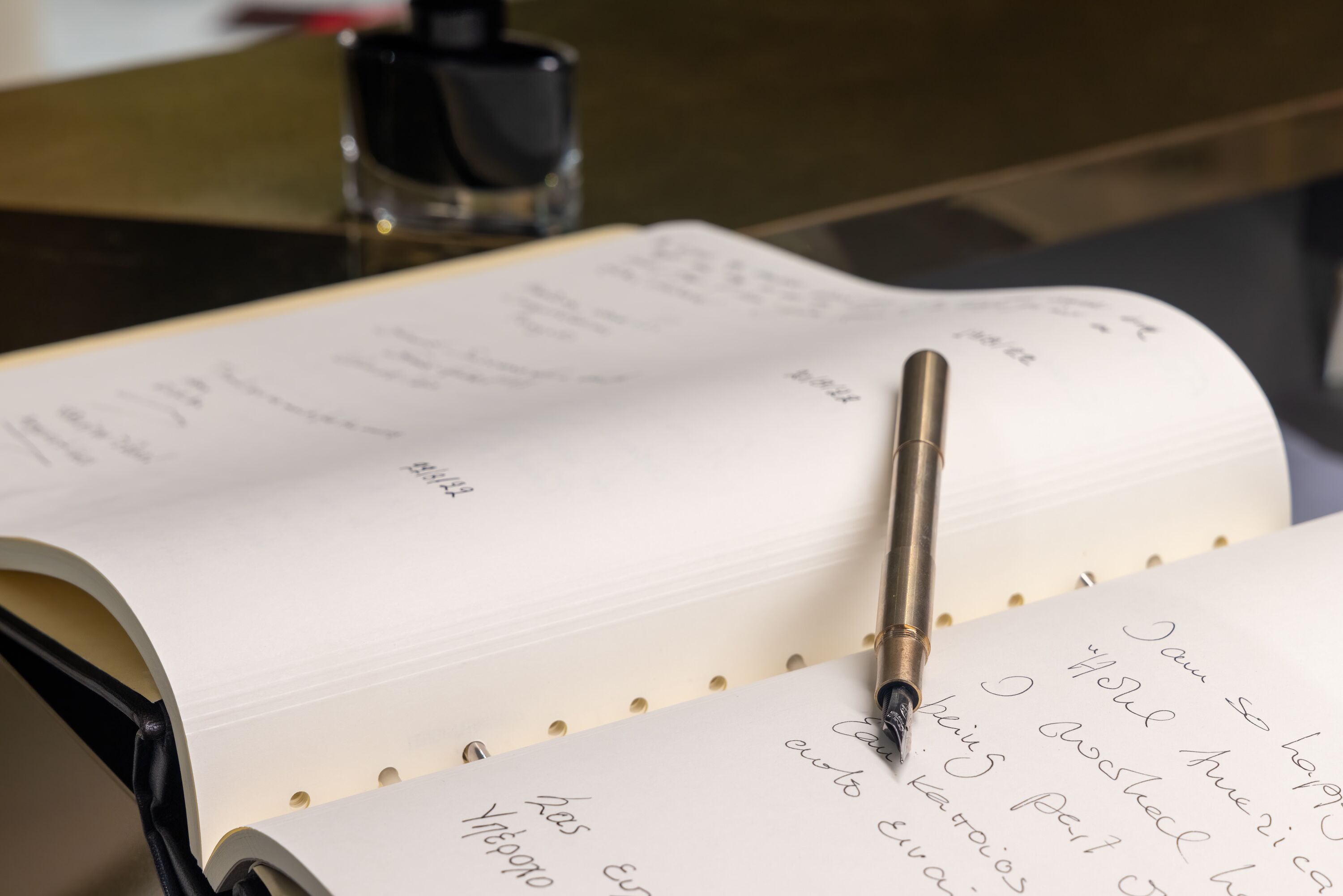 Una libreta abierta con texto escrito a mano y un bolígrafo encima.