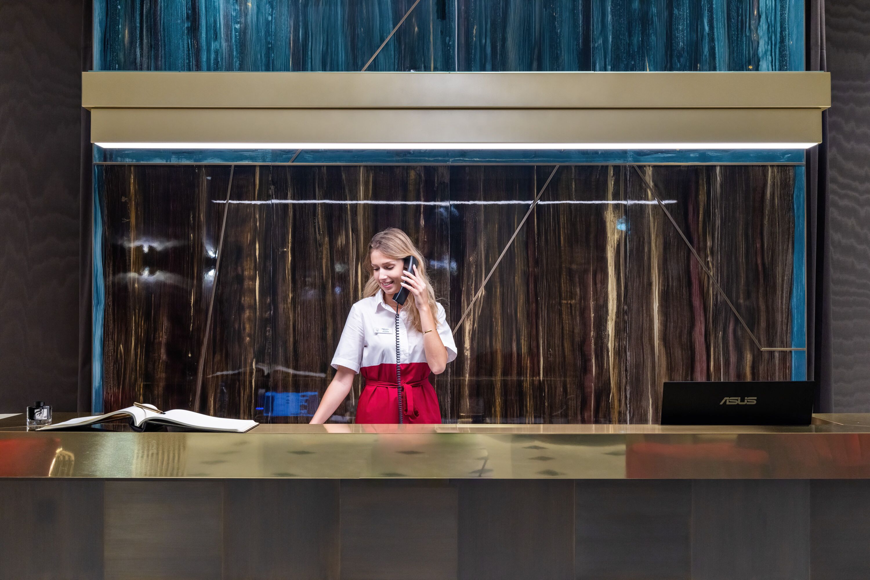 Een receptiebalie met een laptop, een boek en een telefoon.