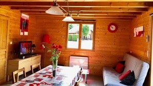 Een knus cabin interieur met een houten eettafel, een bank en een televisie in de hoek.