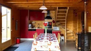 Een houten interieur met een eettafel, rode kasten, een keuken en een trap.