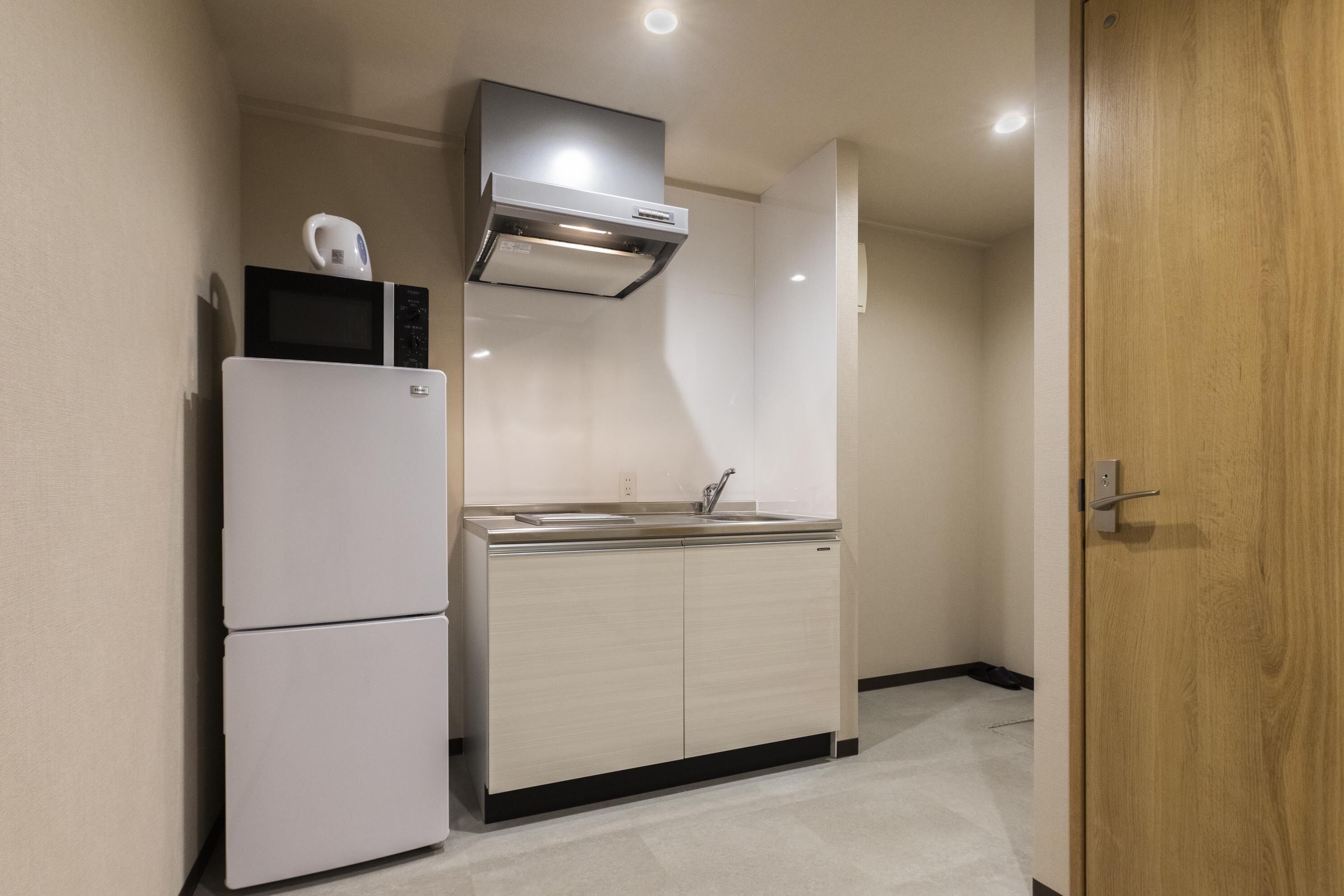 A compact kitchen with a refrigerator, microwave, and sink.