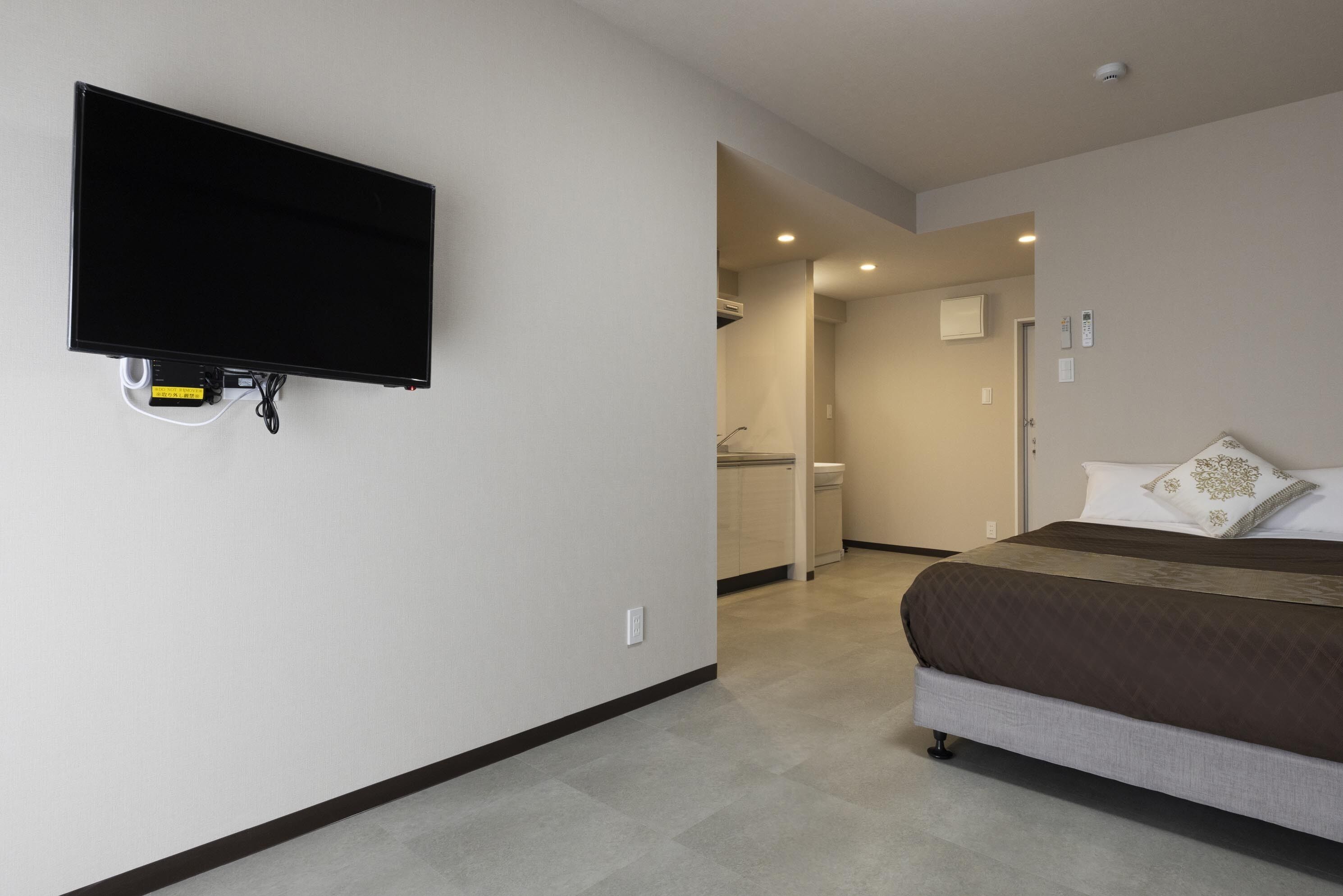 Een hotelkamer met een bed, een aan de muur bevestigde televisie en een badkamer door een open deur zichtbaar.