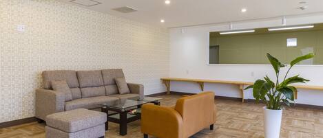 A modern living room with a sofa, ottoman, and coffee table, a bench, and a potted plant.