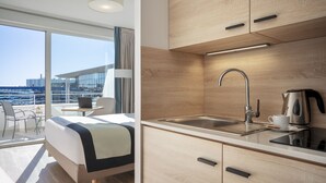 A modern hotel room with a balcony, a bed, a desk, and a kitchenette. - Residhome Nice Aéroport (Nice)