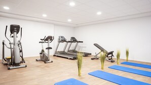 A gym with cardio machines, a stationary bike, and blue exercise mats. - Residhome Nice Aéroport (Nice)