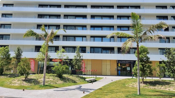 A multi-story hotel with a modern design, featuring balconies on each floor, a landscaped courtyard with palm trees, and signage for a restaurant and a business center. - Residhome Nice Aéroport (Nice)