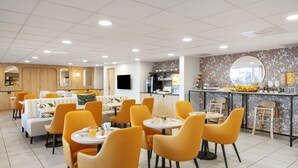 A modern dining area with yellow chairs and tables, a kitchen area, and a counter with food and drink options. - Residhome Nice Aéroport (Nice)