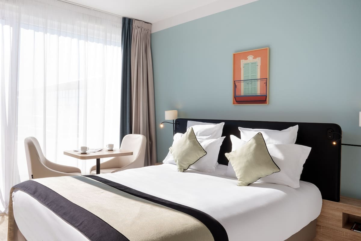 A hotel room with a large bed, a desk, and a chair.