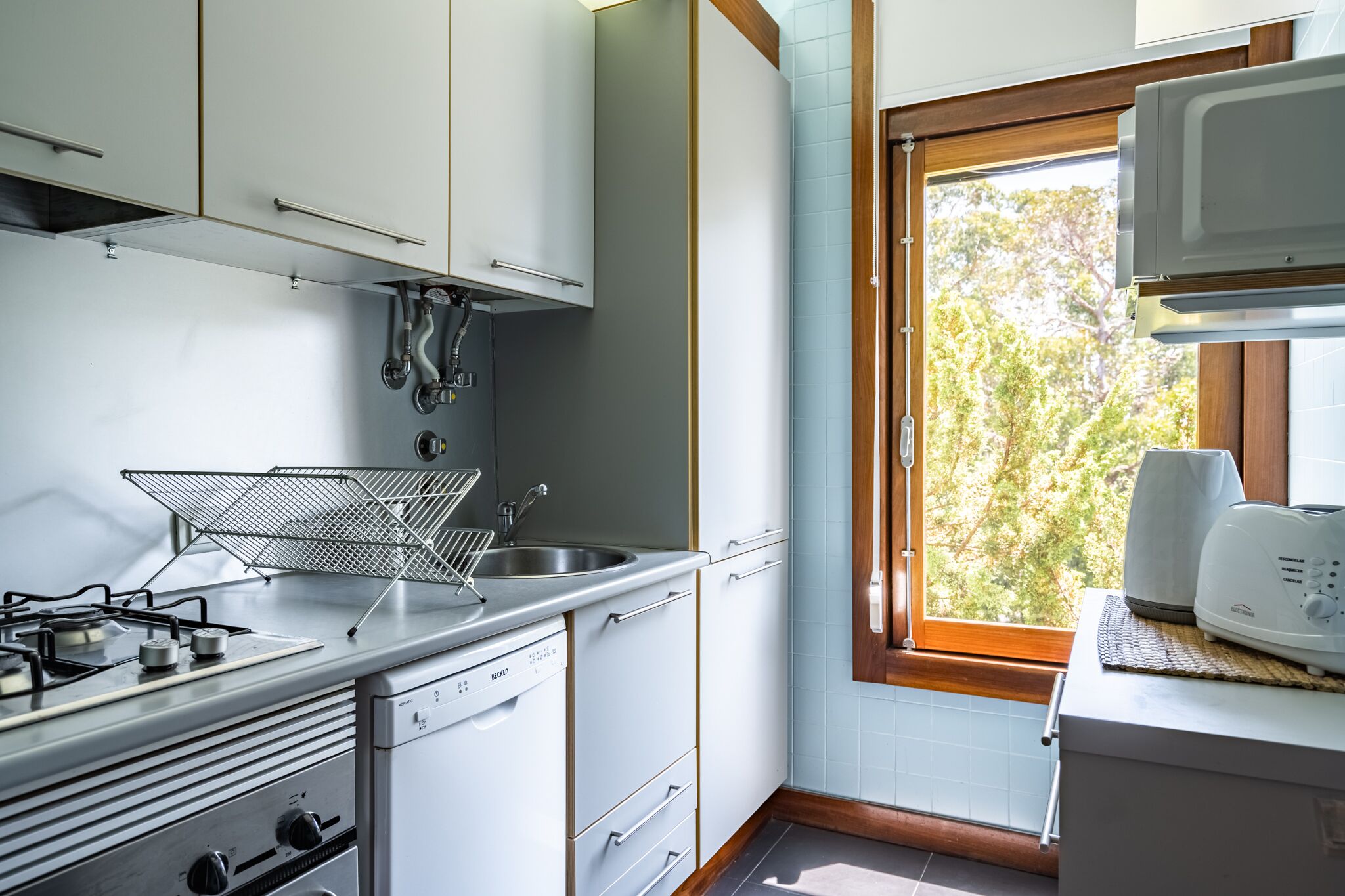 A compact kitchen with a gas stove, sink, and white cabinets.