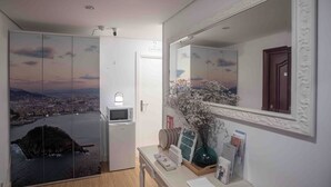 A hotel room with a cityscape view, a microwave, a small table with a vase and magazines, and a door labeled "2". - Pensión Gurtxu by Sun Sebastián (San Sebastián)
