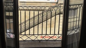 A view through a window with a metal railing, a stone staircase, and a building facade with a window and some graffiti. - Pensión Gurtxu by Sun Sebastián (San Sebastián)