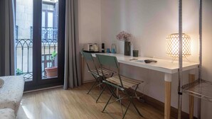 A modern room with a wooden floor, a white desk with a lamp, a chair, and a balcony with a view. - Pensión Gurtxu by Sun Sebastián (San Sebastián)