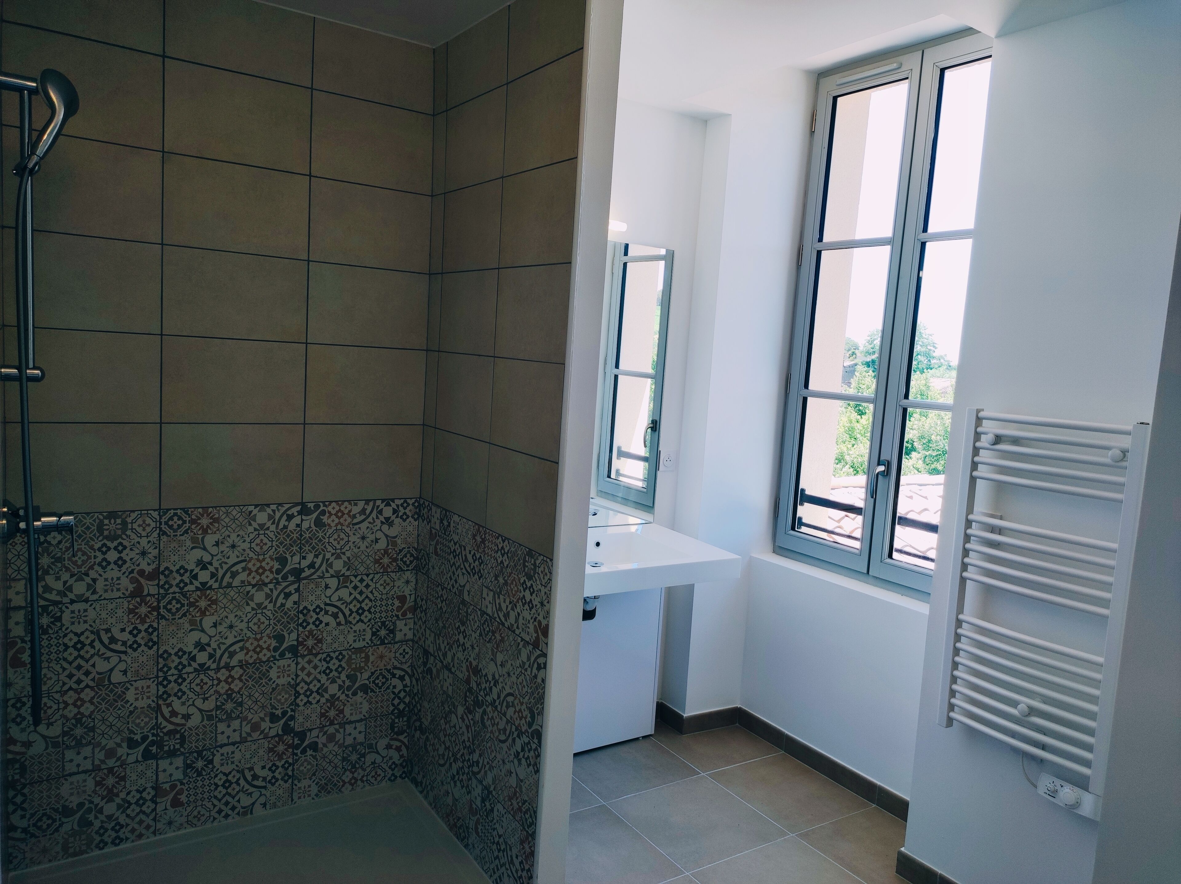 Une salle de bain avec une douche, un lavabo et une fenêtre.