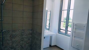 Une salle de bain avec une douche, un lavabo et une fenêtre.