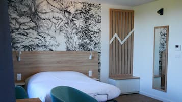 Una camera da letto con un letto, una scrivania, una sedia, uno specchio e un murale a tema naturalistico.