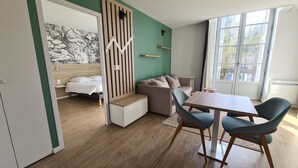 Un dormitorio moderno con cama, sofá, mesa de comedor y ventana con vistas.
