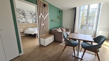 Quarto moderno com cama, sofá, mesa de jantar e janela com vista.