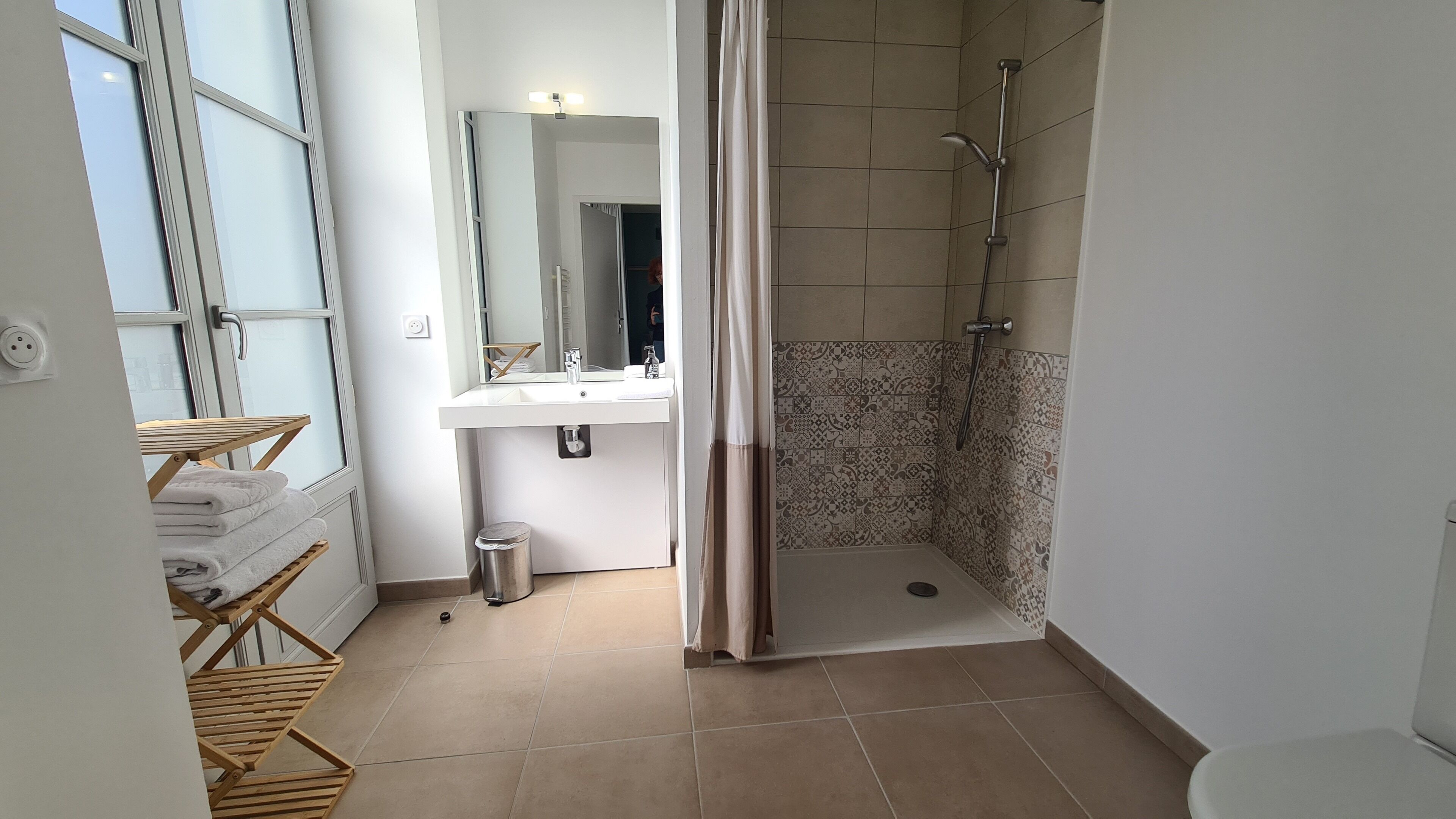 Une salle de bain avec une douche, un lavabo, un miroir et une fenêtre.