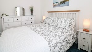 Une chambre à coucher avec un lit, une commode, une table de chevet, une lampe et un tableau au mur.