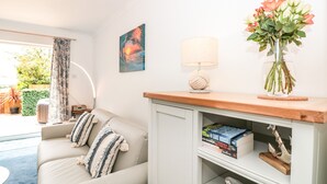 Un salon confortable avec un canapé, une lampe, un vase de fleurs et une bibliothèque remplie de livres.