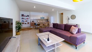 Ein modernes Wohnzimmer mit einem violetten Sofa, einem Holztisch und einem Essbereich mit Stühlen und Tisch.