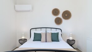 Ein ordentlich gemachtes Bett mit weißen und grünen Kissen und zwei Nachttischlampen, dazu Wanddeko.