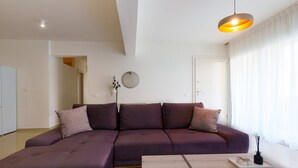 Ein modernes Wohnzimmer mit einem Ecksofa, einem Couchtisch und einer Pendelleuchte.
