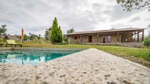 A stone house with a pool, a lounge chair, and a tall tree. - Chão do Rio - Turismo de Aldeia (Seia)