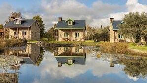 Three stone buildings with green roofs, a pond in the foreground, and trees in the background. - Chão do Rio - Turismo de Aldeia (Seia)