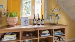 A wooden table with a potted plant, wine bottles, and books. - Chão do Rio - Turismo de Aldeia (Seia)