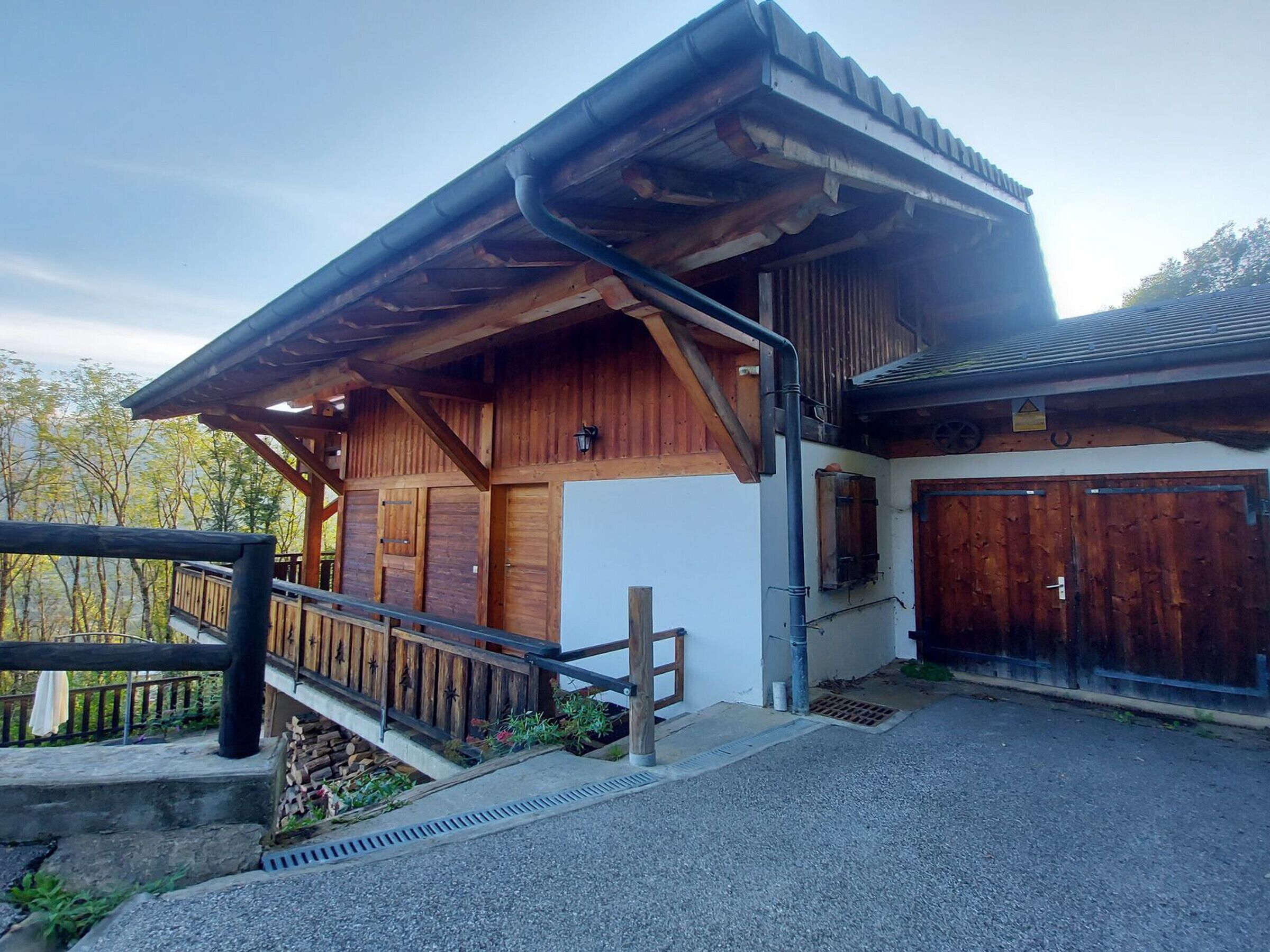 Une construction en bois dotée d’un porche abrité, d’un garage et d’un espace clôturé.