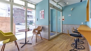 Un intérieur moderne avec un plancher en bois, une entrée avec une porte en verre et un aménagement comprenant des sièges, notamment une chaise jaune et une table ronde.