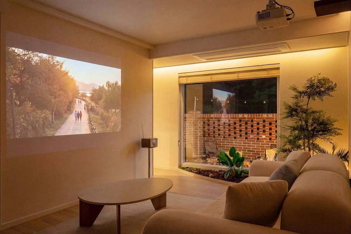A living room with a projector screen, a sofa, a coffee table, and a brick wall.