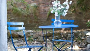 Un juego de mesa y sillas de metal azul con un florero de flores blancas.