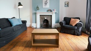 Una sala de estar con chimenea, dos sofás, una mesa de centro y una lámpara de pie.