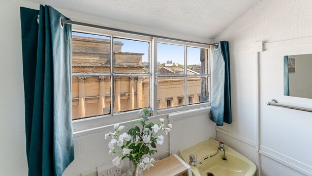 Un baño con ventana, lavamanos y espejo.