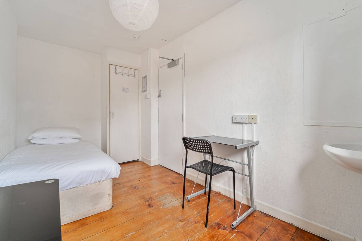 Una habitación pequeña y limpia con una cama, un escritorio y una silla.