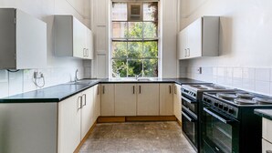 Una cocina con armarios blancos, encimera negra, ventana y estufa.