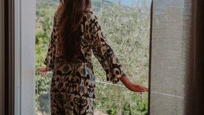 A person standing by a window with a view of greenery and mountains. - Villa Dolce Bellezza (Salò)