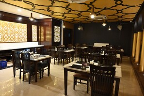 Un restaurant doté de nombreuses tables et chaises, d’un plafond orné de motifs et de panneaux muraux décoratifs.